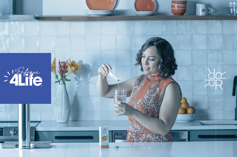 Una mujer en una cocina agregando un sobre de polvo Immune Boost a un vaso de agua para reforzar su sistema inmunológico.