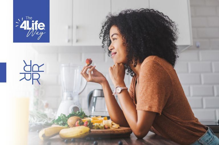 woman in a kitchen holding a strawberry