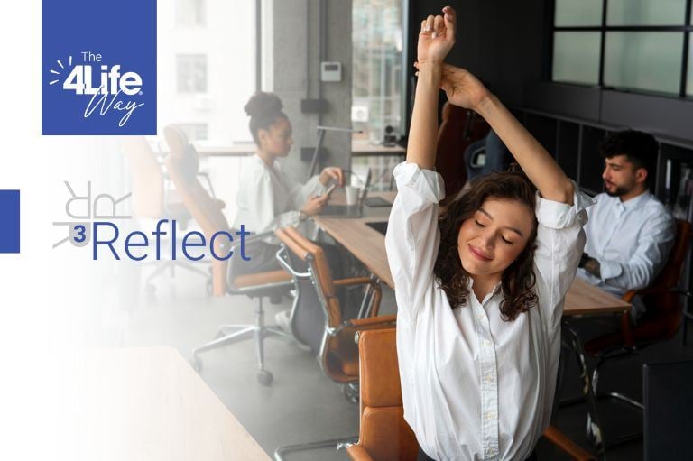 A woman in the office stretching her arms in a peace-mind expression