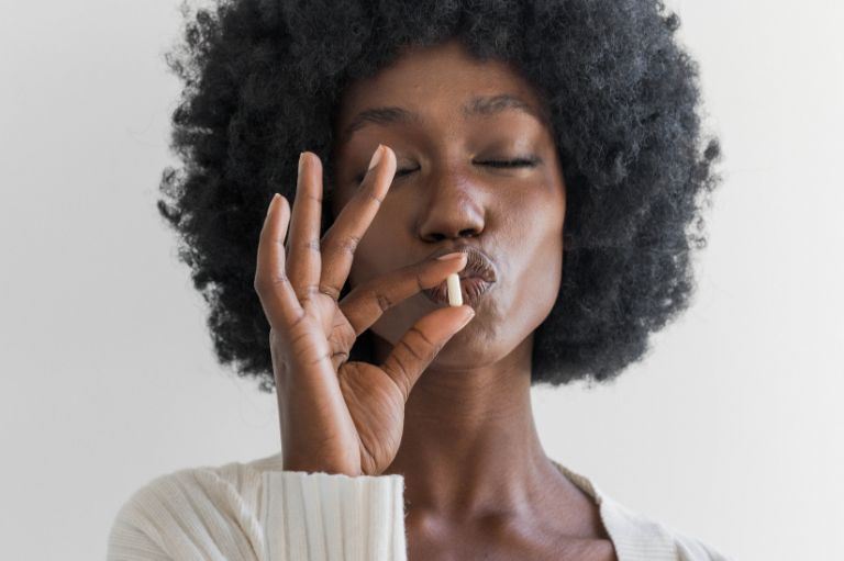 a girl with her eyes closed holding a pill near her mouth