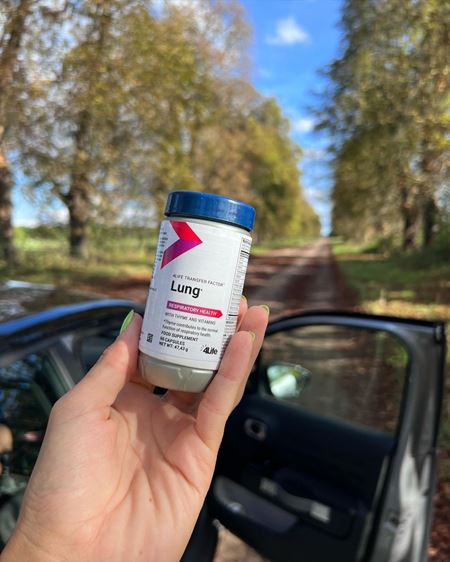 A hand holding a packet of tf lung on a field 